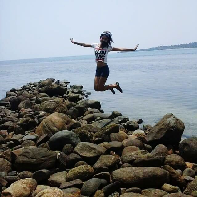 WOMAN JUMPING AT BEACH AGAINST SKY