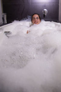 Young woman taking bubble bath in bathtub