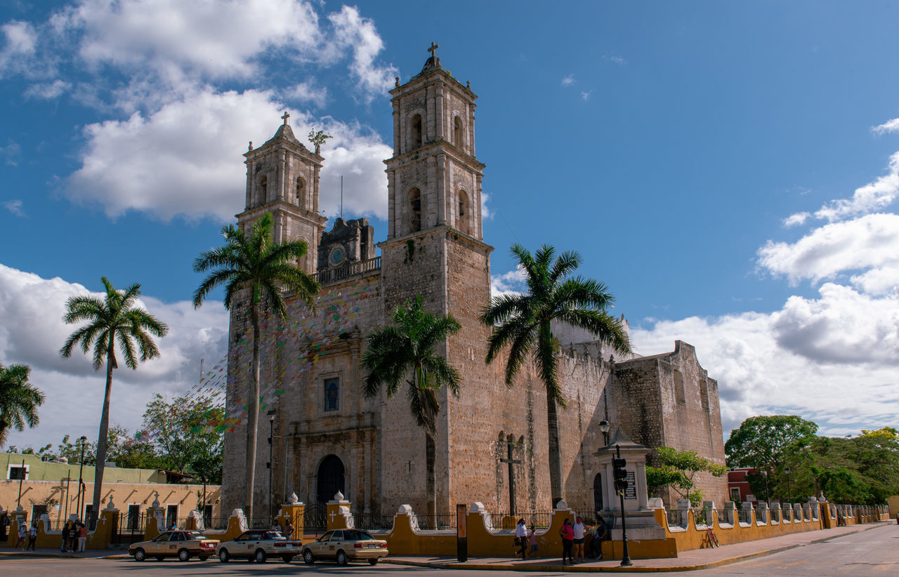 architecture, palm tree, sky, built structure, tropical climate, tree, building exterior, travel destinations, cloud, landmark, nature, building, religion, city, place of worship, plant, travel, history, the past, town, vacation, belief, tourism, street, spirituality, town square, tower, outdoors, blue, cityscape, transportation, holiday, day, worship, trip