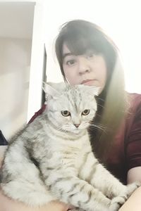 Portrait of young woman sitting cat at home