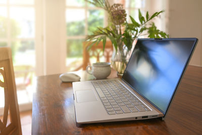 Midsection of woman using laptop at home