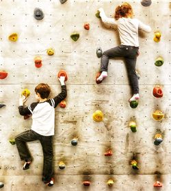 Full length of siblings climbing on wall