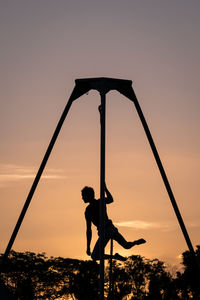 Silhouette woman playing soccer against sky during sunset