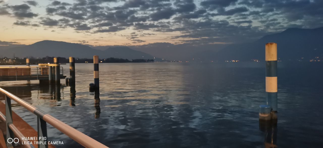 WOODEN POSTS ON LAKE AGAINST SKY