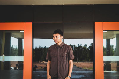 Portrait of young man standing against wall