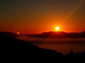 Scenic view of silhouette mountains against romantic sky at sunset