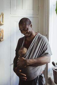 Smiling father looking at baby boy in carrier