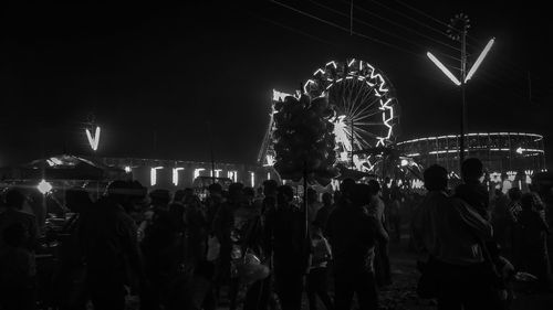 People in amusement park against sky at night