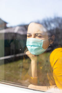 Portrait of young woman seen through glass window