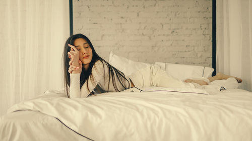 Portrait of young woman sitting on bed at home