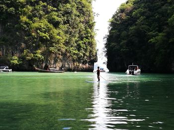 Man sailing on river against trees