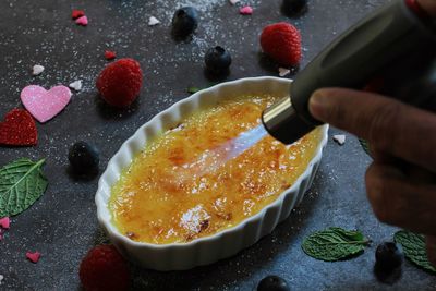 Cropped hand heating food with kitchen torch at table