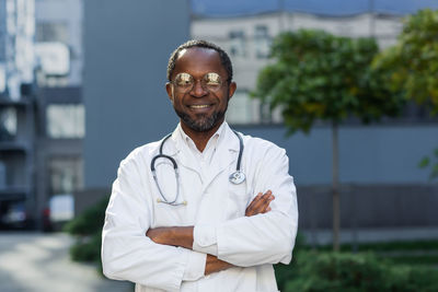 Portrait of doctor standing against trees