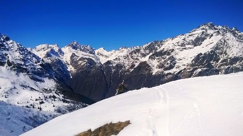 Scenic view of snow covered mountains against clear blue sky