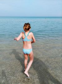 Rear view full length of girl standing on shore at beach