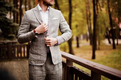 Midsection of businessman wearing suit against trees