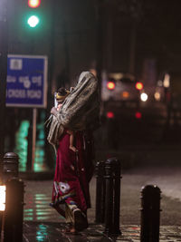 Rear view of woman walking on street at night