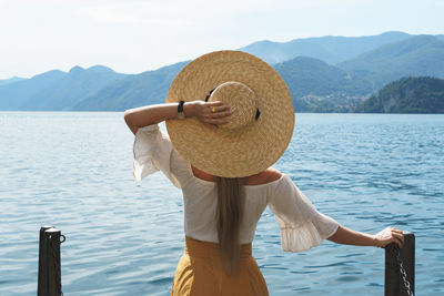 Rear view of woman standing by sea against sky