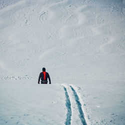 Rear view of man walking on snow covered landscape