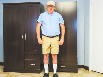 Portrait of young man standing against door