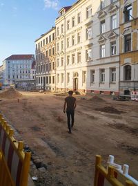 Rear view of man walking on street by buildings
