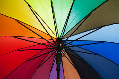 Low angle view of multi colored umbrella against blue sky