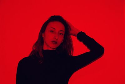 Portrait of young woman against red background