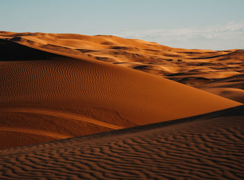 Sand dunes in desert against sky