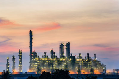 Illuminated factory against sky during sunset