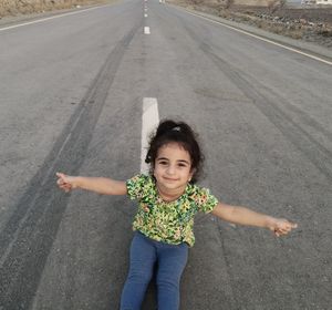 Portrait of smiling girl sitting on road