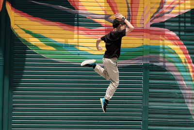 Full length of boy jumping against shutter