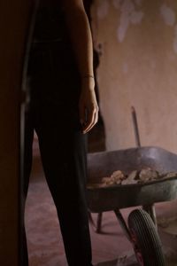 Midsection of woman standing by wheelbarrow