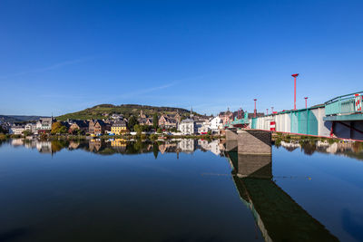 Buildings by river against blue sky