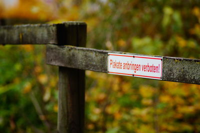 Close-up of warning sign on wooden fence