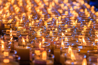 Full frame shot of illuminated candles in glasses at church