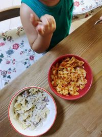 Midsection of boy by bowl with pastas