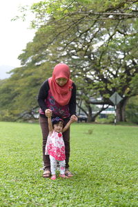 Full length of woman standing on grass against trees