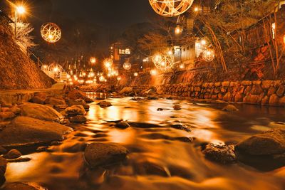 Reflection of illuminated trees in water at night