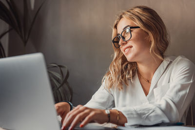 Portrait of young woman using laptop at table