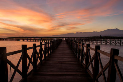 Pier over sea against sky during sunset