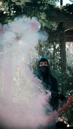 Portrait of young man holding smoke bomb