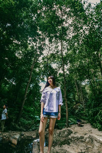 Full length of woman standing in forest