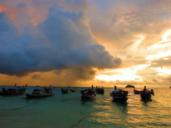 Boats moored in sea against sky during sunset