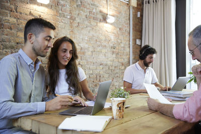 Friends using laptop while sitting at office