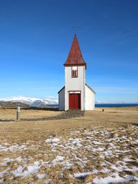 Building on snow covered land against blue sky