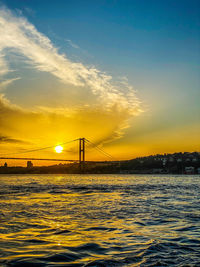 Bridge over sea against sky during sunset