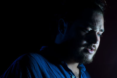 Portrait of young man against black background