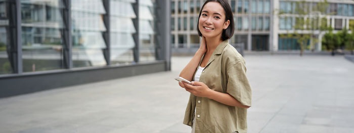 Portrait of young woman standing in city