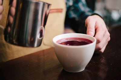 Close-up of woman holding coffee cup on table