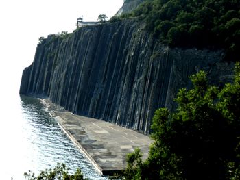 Scenic view of waterfall by cliff against sky